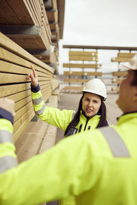 Multiracial coworkers examining planks stacked at industry