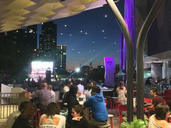 Crowd at illuminated city against sky at night