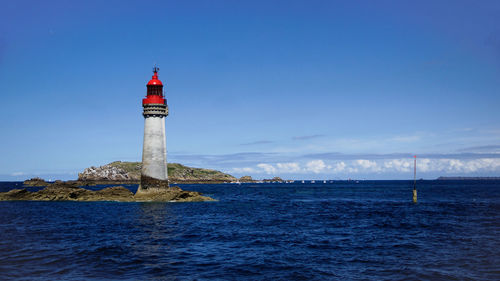 Lighthouse by sea against sky