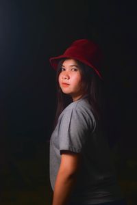 Portrait of teenage girl looking away against black background