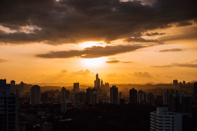 Modern buildings in city against sky during sunset