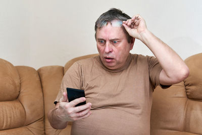 Portrait of mature man using mobile phone on sofa