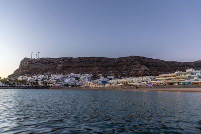 Scenic view of sea by buildings against clear sky