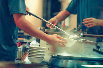 Midsection of men preparing food in restaurant kitchen