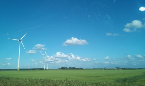 Windmill on field against blue sky