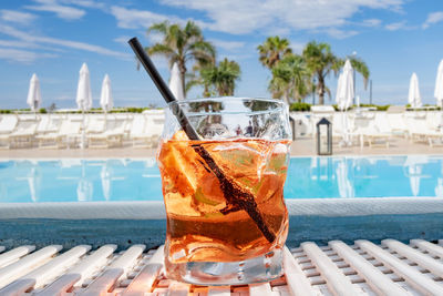 Close-up of drink on table by swimming pool against sky