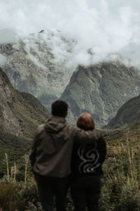 Rear view of man standing on mountain against sky