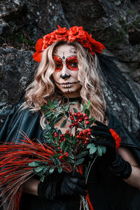 Closeup portrait of calavera catrina. young woman with sugar skull makeup and red flowers. dia 