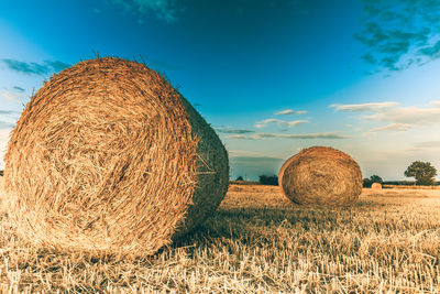 Hay bales on field against sky