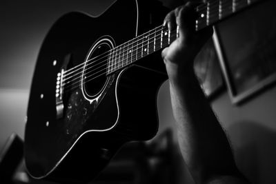 Cropped hand of man holding guitar at home