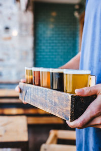 Midsection of man carrying various beer glasses in restaurant