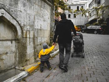 Rear view of men walking on street in city