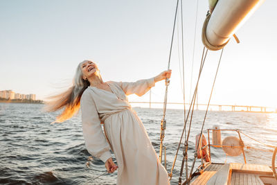 Smiling senior woman standing on boat at sea