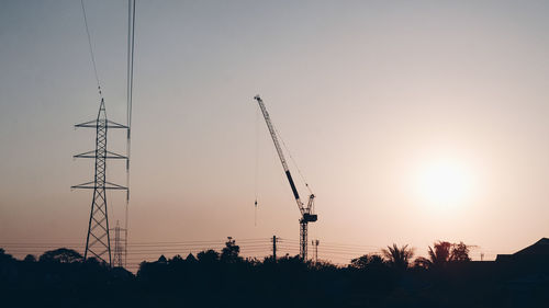 Low angle view of silhouette cranes against sky during sunset