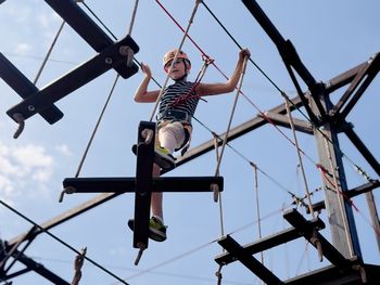 Low angle view of man standing on swing