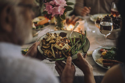 Man passing food plate to woman while sitting at dining table during party