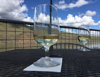 Close-up of wine in glass on table against sky