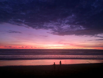 Silhouette people standing on beach against sky during sunset