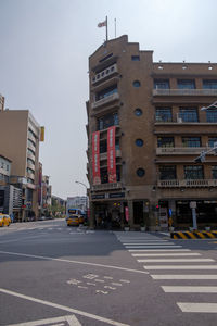 Road by buildings against sky