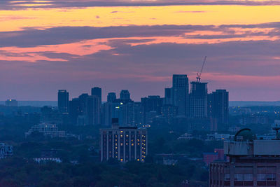 Modern buildings in city against romantic sky at sunset