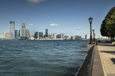 Sea by modern buildings against sky in city