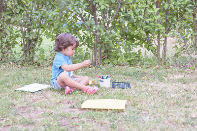 Young woman using mobile phone while sitting on field