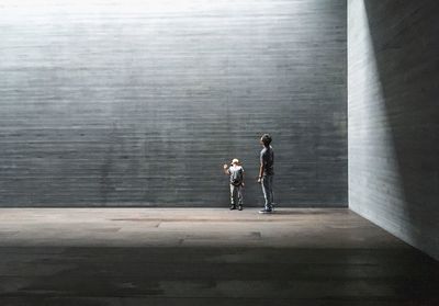 Rear view of man and woman walking on concrete wall