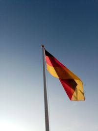 Low angle view of flag against clear blue sky