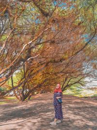 Full length of a girl standing in autumn tree