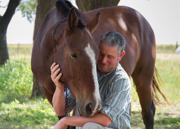 Man standing with horse against trees