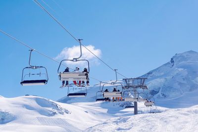 Ski lift over snowcapped mountains against clear blue sky