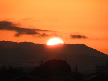 Scenic view of silhouette mountains against orange sky