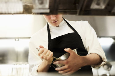 Midsection of male chef mixing food in bowl in commercial kitchen