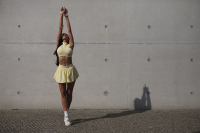 Full length of woman standing against wall