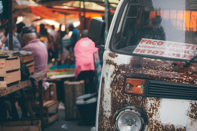 Very old van and some people sitting at market selling fruits