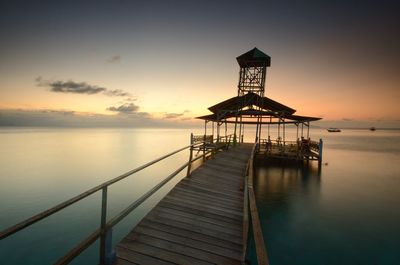 Pier over sea against sky during sunset