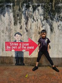 Portrait of a smiling girl standing against wall