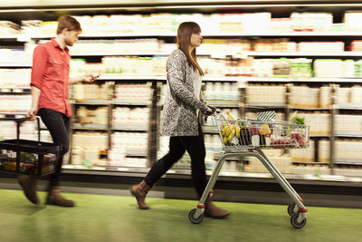 Young couple walking by shelves at supermarket