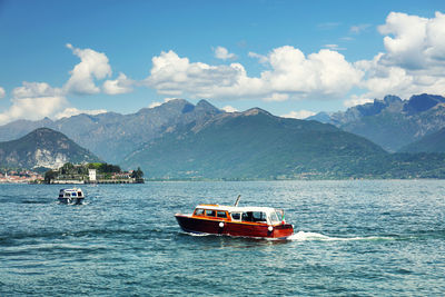 Ship sailing on sea against mountains