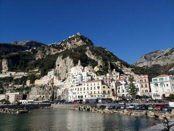 Buildings by town against clear blue sky