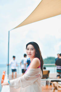 Portrait of young woman standing against sky