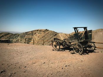 Broken cart on field against clear sky