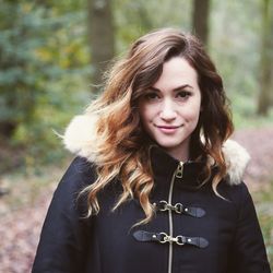 Portrait of smiling young woman against trees in forest