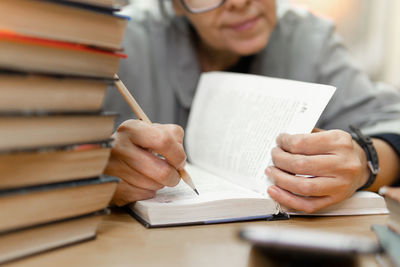 Midsection of woman writing in book