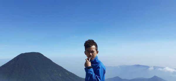 Man standing on mountain against blue sky