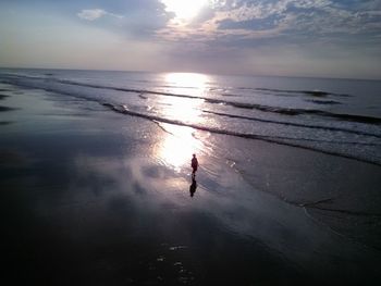 Man on beach against sky during sunset