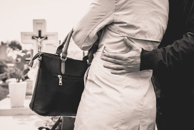 Midsection of couple standing against cross