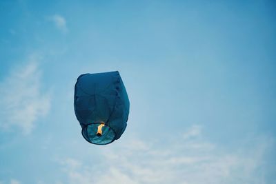 Low angle view of lit lantern flying against sky