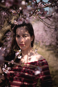 Portrait of a beautiful young woman by cherry blossom tree