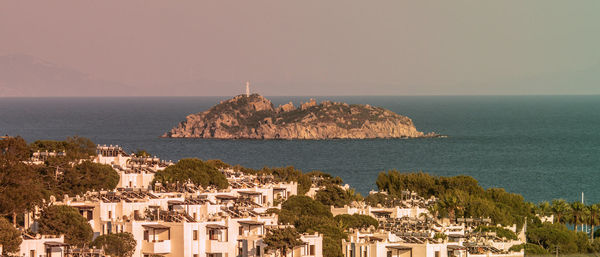 Houses by sea against clear sky and island